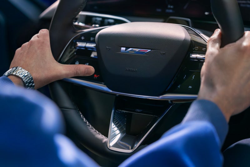Close-up of a Man About to Press the V-Button on the 2026 OPTIQ-V Steering Wheel | Home Motors Cadillac in SANTA MARIA CA