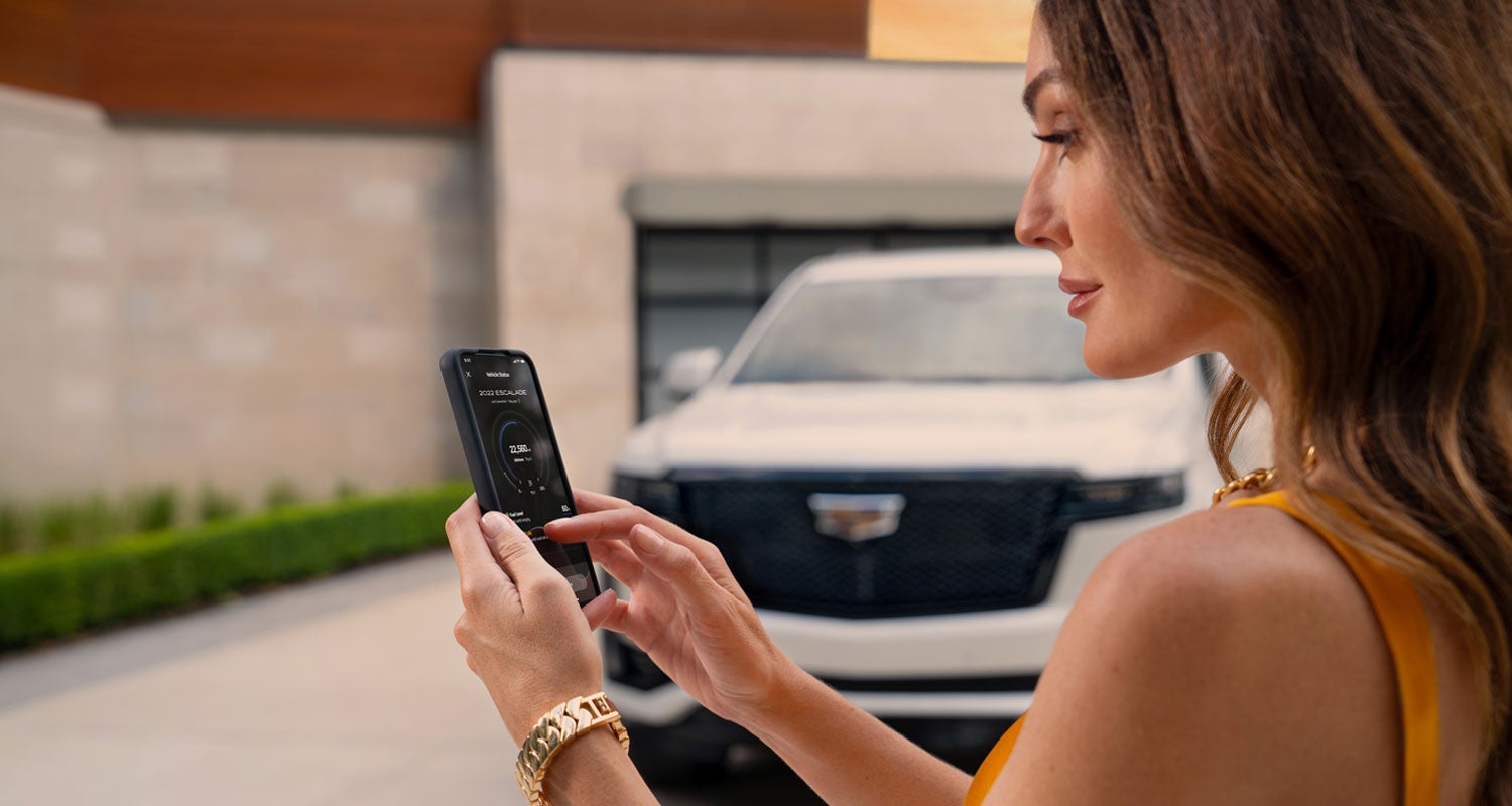 lady checking her mobile with a Cadillac vehicle background | Home Motors Cadillac in SANTA MARIA CA